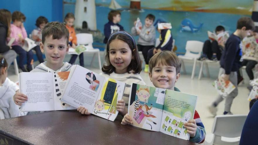 Dellos alumnos enseñando los llibros de la biblioteca. | LNE