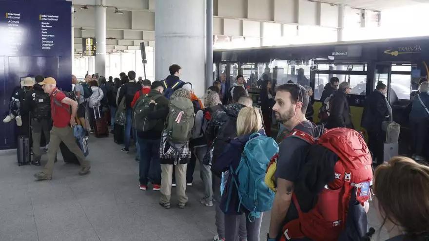 Pasajeros aguardan para coger un autobús, ayer, en el Aeropuerto de Santiago-Rosalía de Castro.