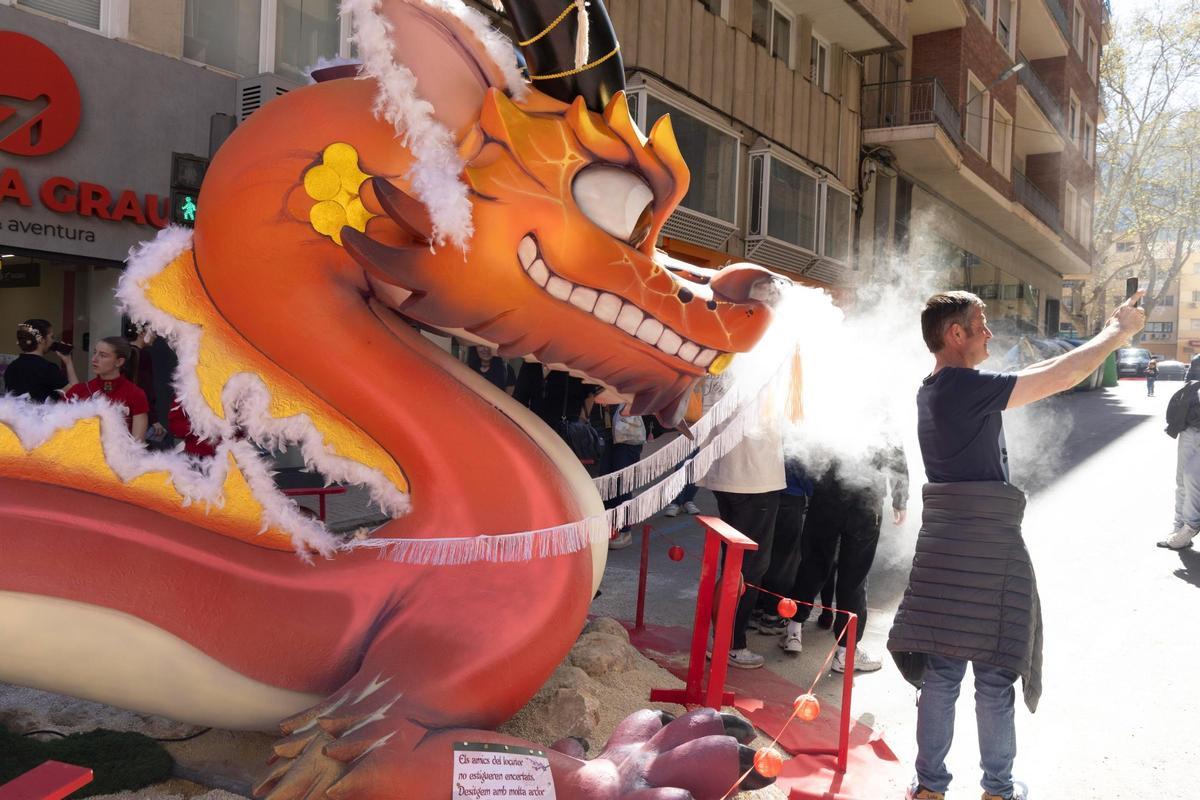 Un hombre en manga corta se hace una foto con el dragón de la Falla República Argentina de Xàtiva.