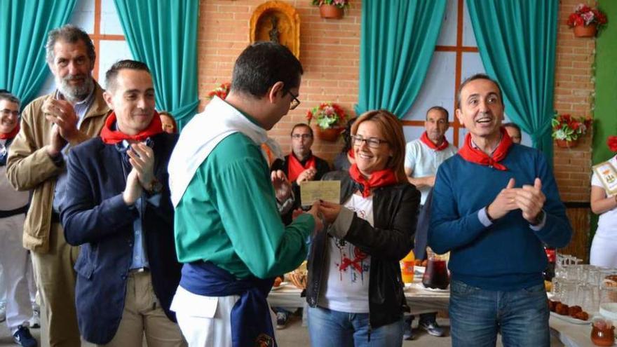 Un miembro de la peña San Isidro, donde se celebró el acto, recoge el cheque de la Diputación.