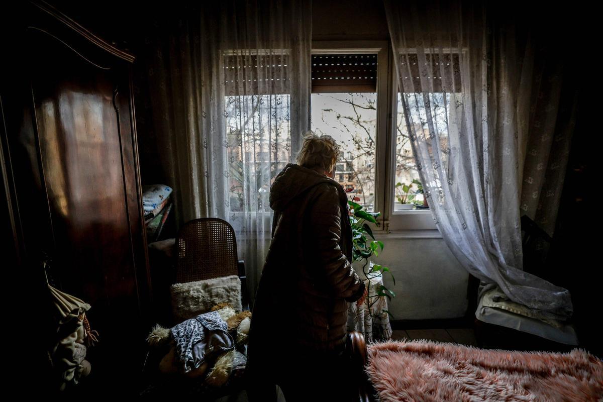 Núria, vecina de 89 años, mira a través de la ventana de la vivienda donde vive desde 1958, en Barcelona.