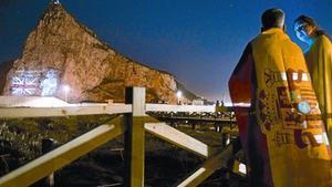 Una pareja mira desde la Línea de la Concepción la proyección de la imagen de Isabel II en el Peñón, en junio del 2012, cuando las autoridades de Gibraltar celebraron el 60º aniversario del ascenso al trono de la reina.