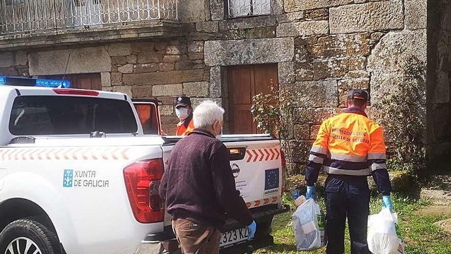 Un voluntario de Protección Civil entregando alimentos a un hombre en Boborás. // FdV