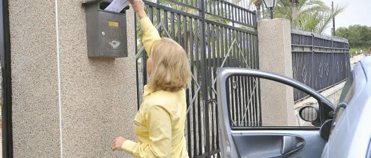 Una trabajadora de Correos durante la entrega de la correspondencia en un buzón de un domicilio de Peña de las Águilas.