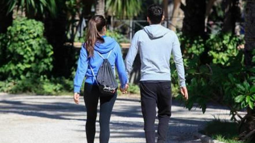 Una pareja de jóvenes, caminando de la mano, por el centro de Elche.