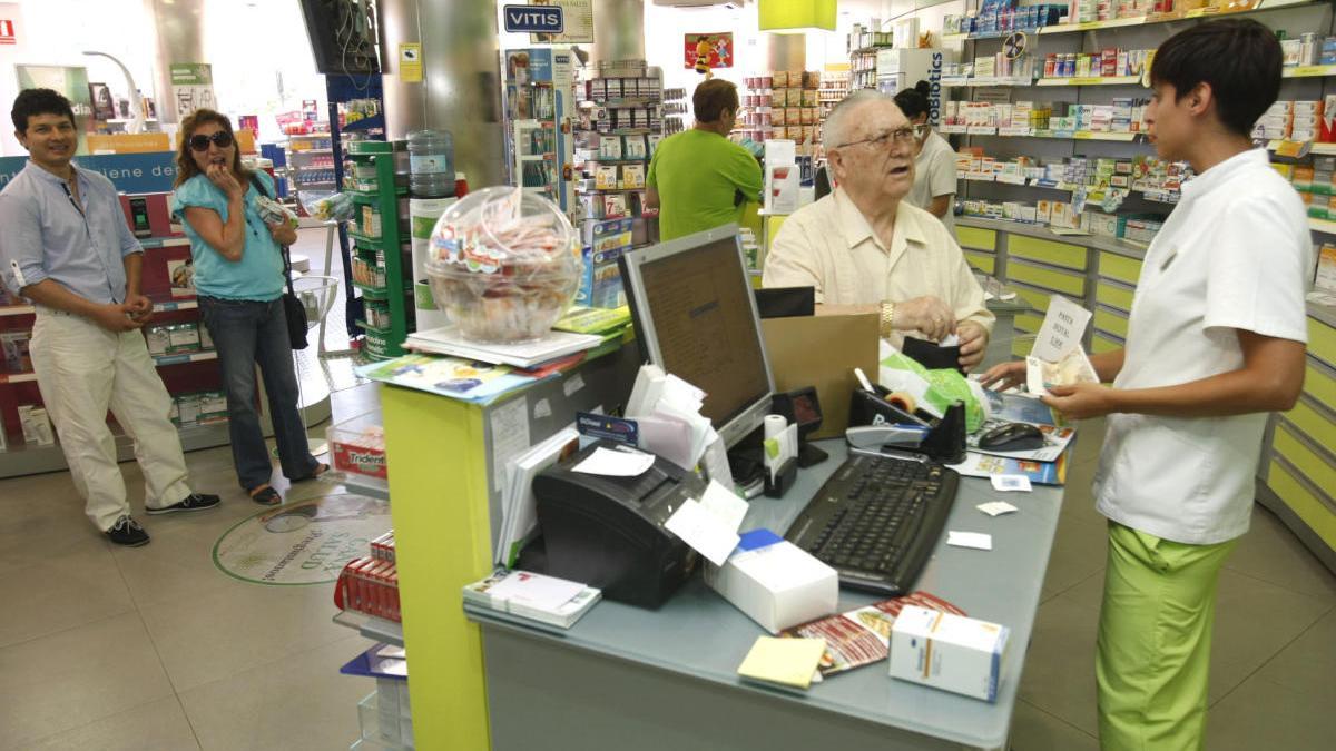 Una farmacéutica atiende a un cliente que acude a por sus medicinas.