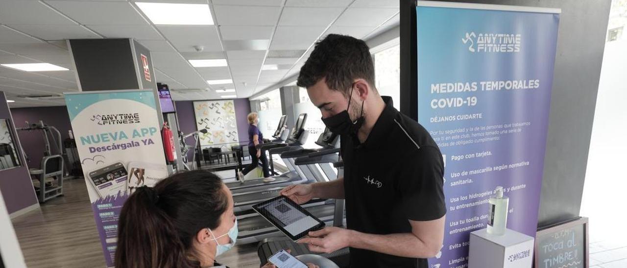 El monitor de un gimnasio escanea el certificado covid de una usuaria