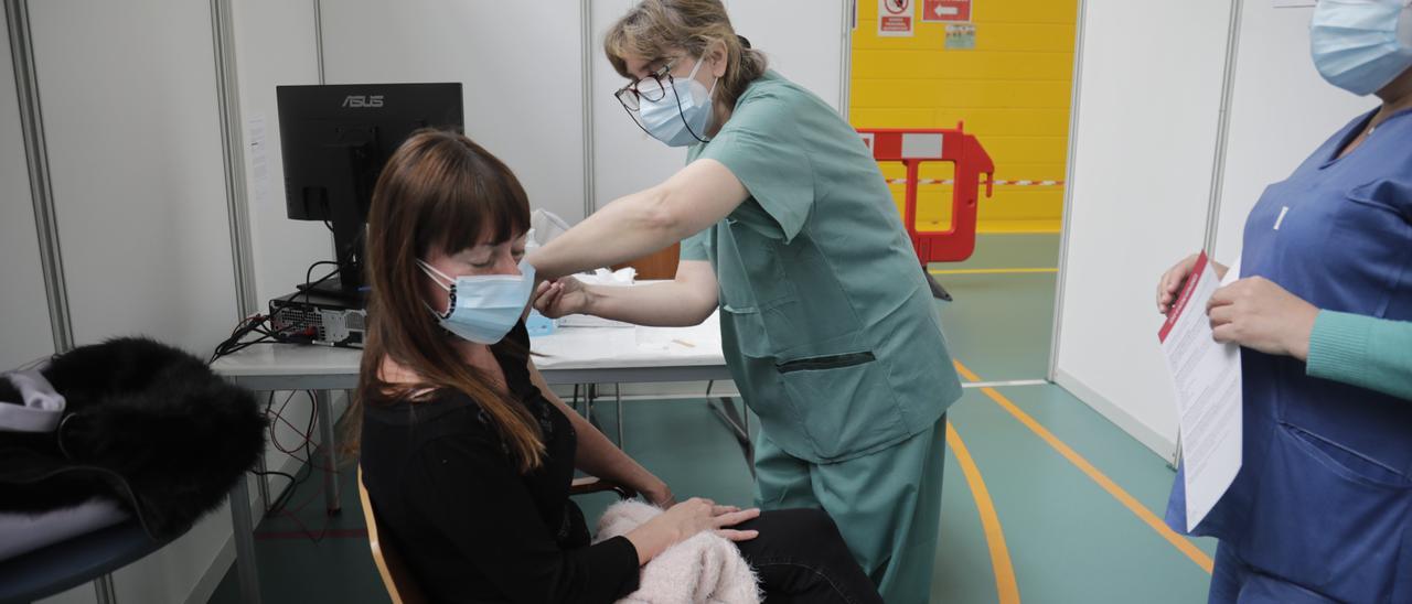 Una joven recibe una dosis de la vacuna contra el coronavirus en el Polideportivo Germans Escalas, en Palma