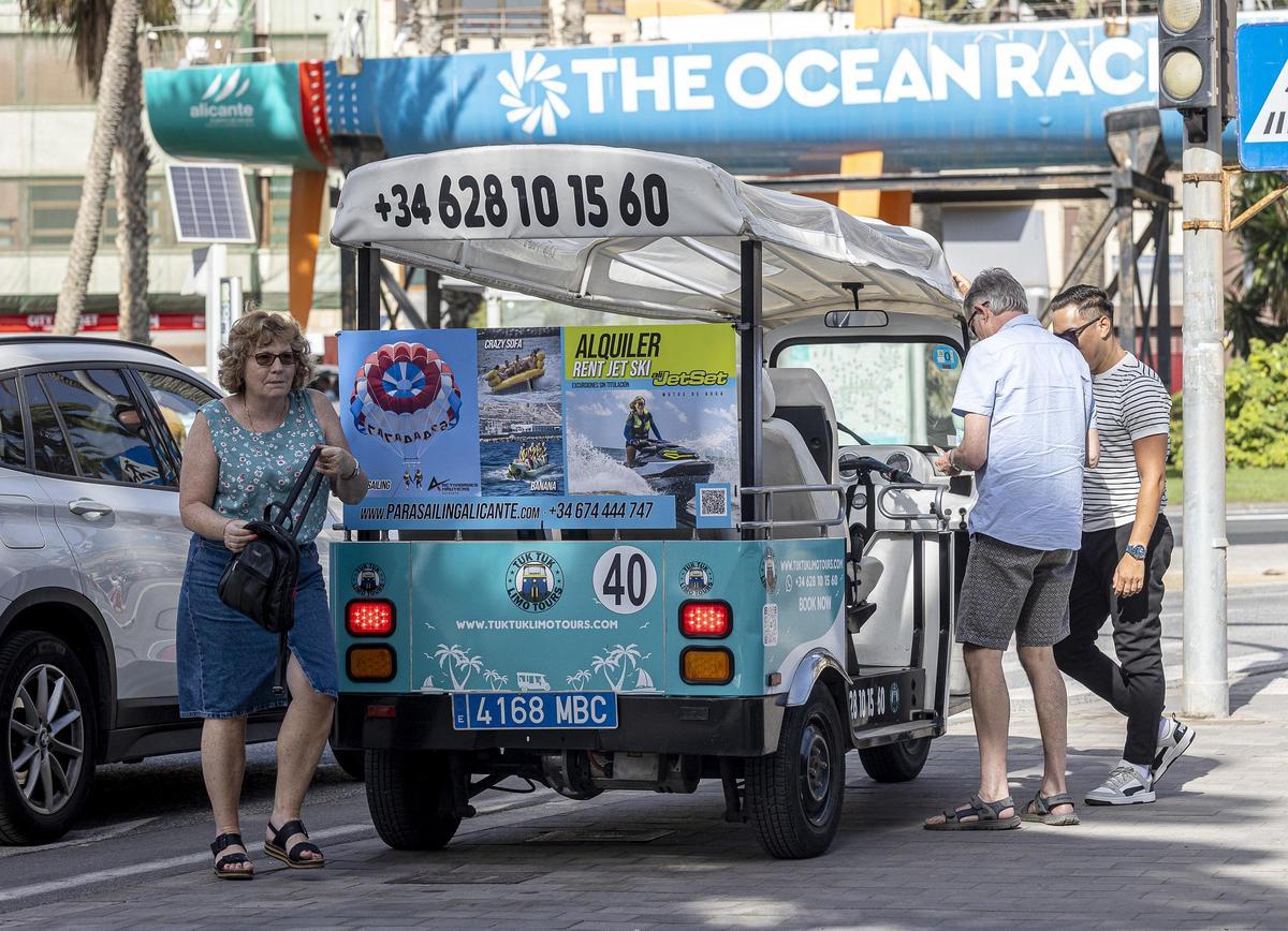 Una pareja de turistas baja del tuk tuk tras su ruta por Alicante, frente a la playad el Postiguet, esta semana.