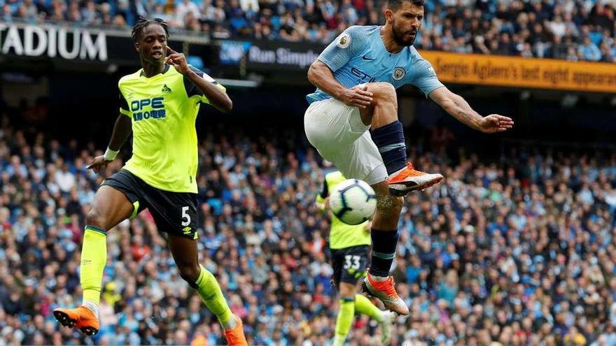 Sergio Agüero remata de forma acrobática ante un defensa del Huddersfield.