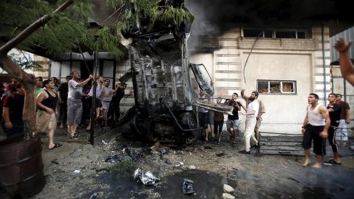 Vecinos de Gaza retiran uno de los vehículos que estalló ayer en la ciudad.