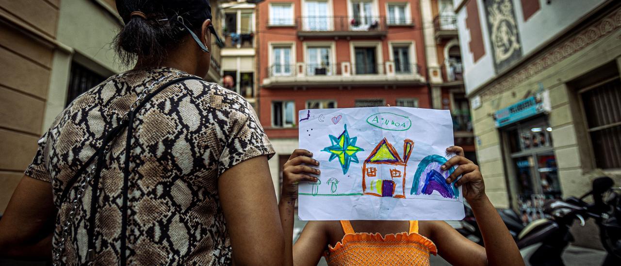 Andrea, de espaldas, y su hija, que sostiene el dibujo en que ha pintado una casa. Fueron desahuciadas en 2021.