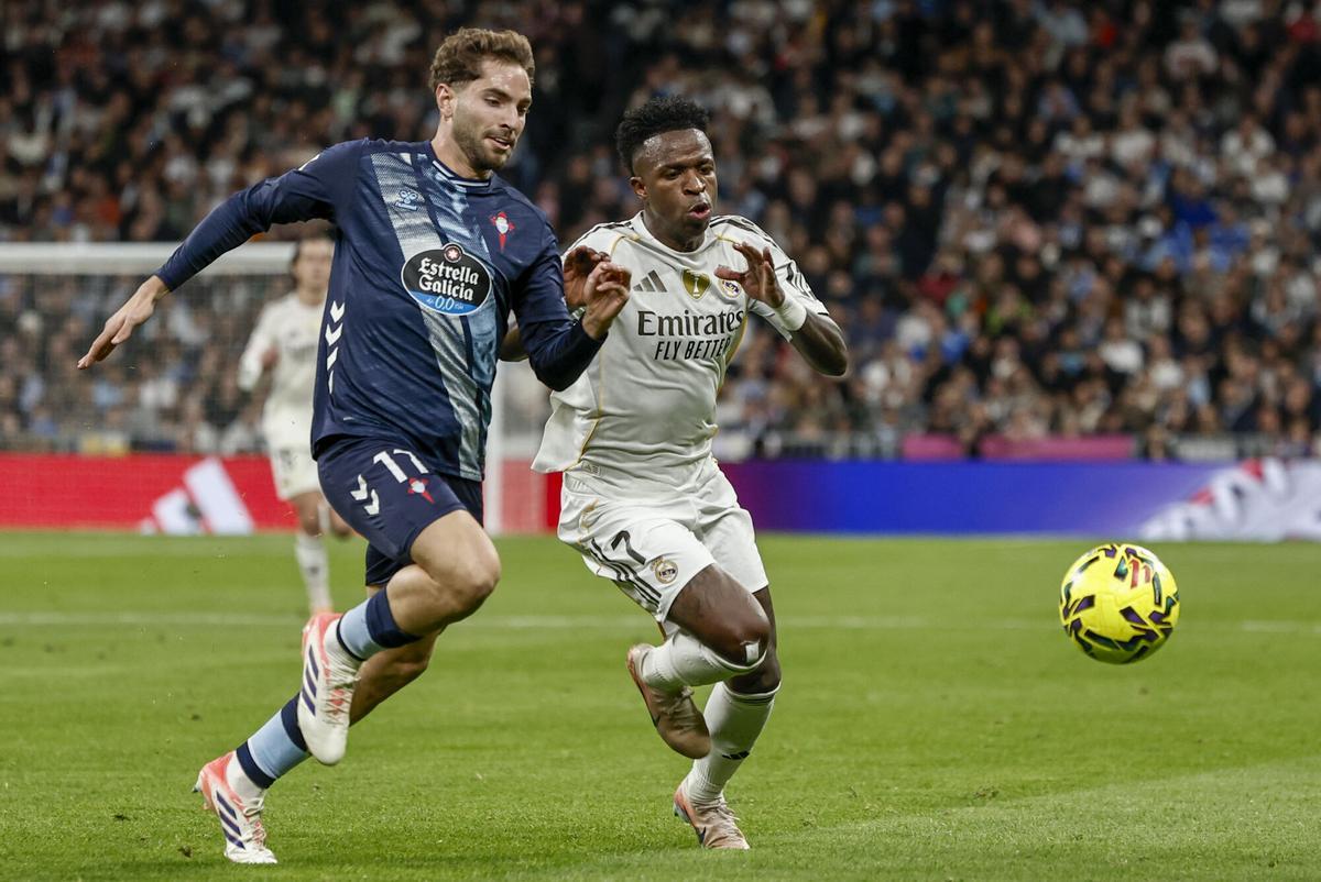 MADRID, 07/12/2025.- El defensa del Celta Javi Rueda (i) pelea un balón con Vinicius Junior, del Real Madrid, durante el partido de LaLiga de fútbol que Real Madrid y Celta de Vigo disputan este domingo en el estadio Santiago Bernabéu. EFE/Sergio Pérez