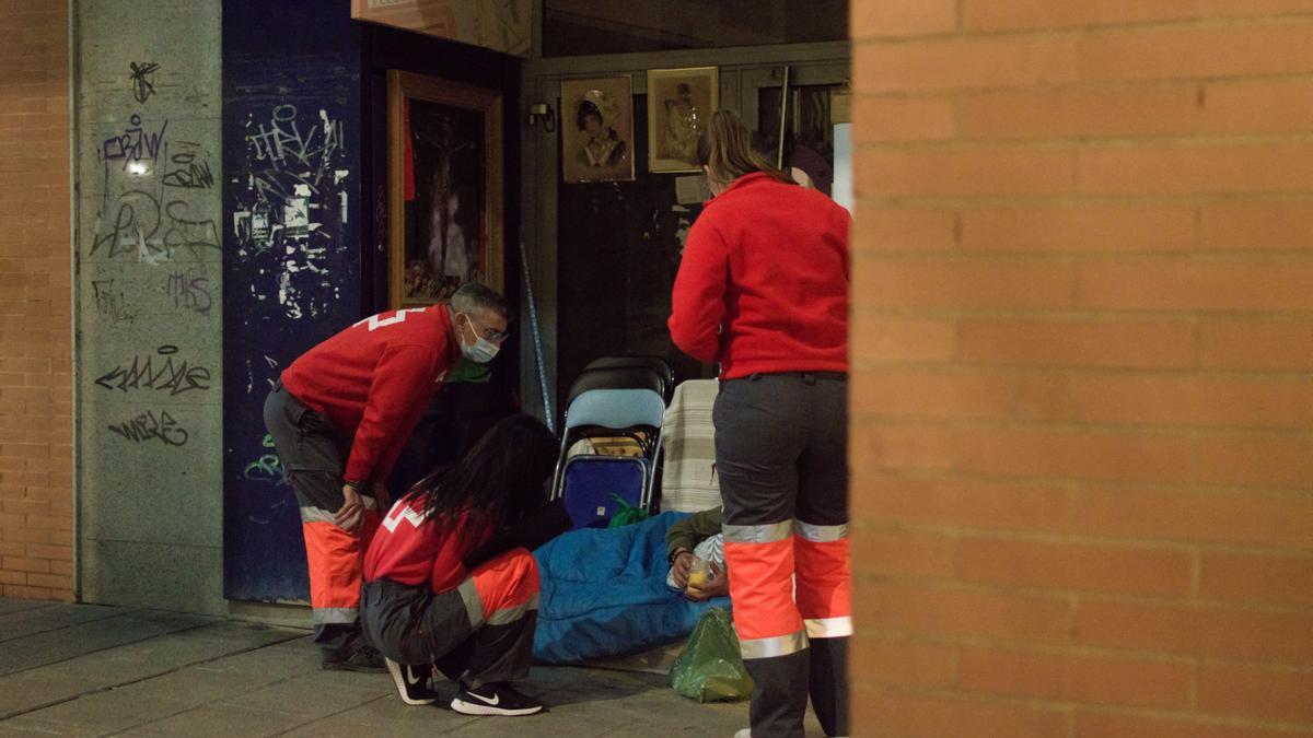 Reparto de ropas de abrigo a una persona sin hogar de Córdoba por parte de voluntarios de Cruz Roja.