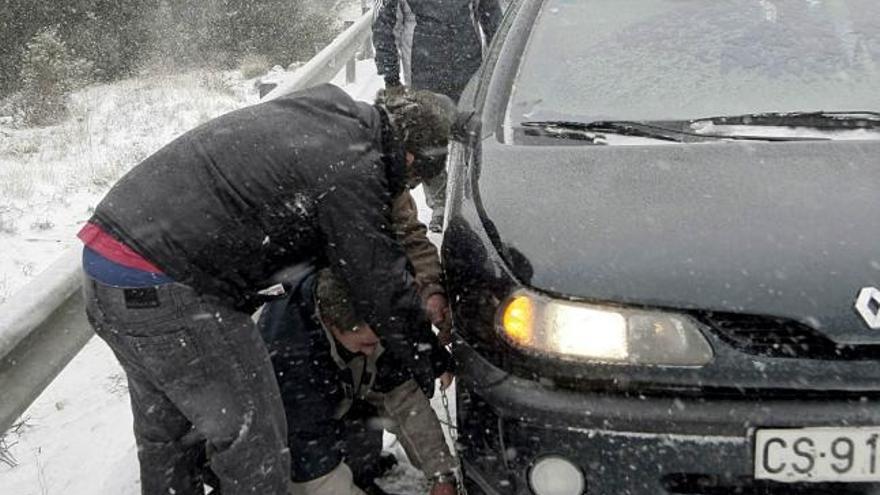 Varios conductores colocan las cadenas durante la nevada de esta tarde en el Puerto de Ares en la comarca del Maestrat en Castellón.