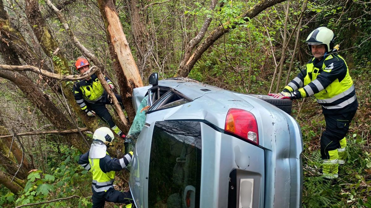 Los bomberos, con el coche accidentado.