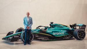 Adrian Newey posa junto a un coche de Fórmula 1 de Aston Martin.