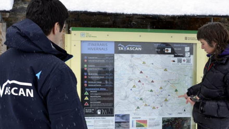 Dues persones observen el plànol que hi ha a peu de pistes de l&#039;estació de Tavascan,