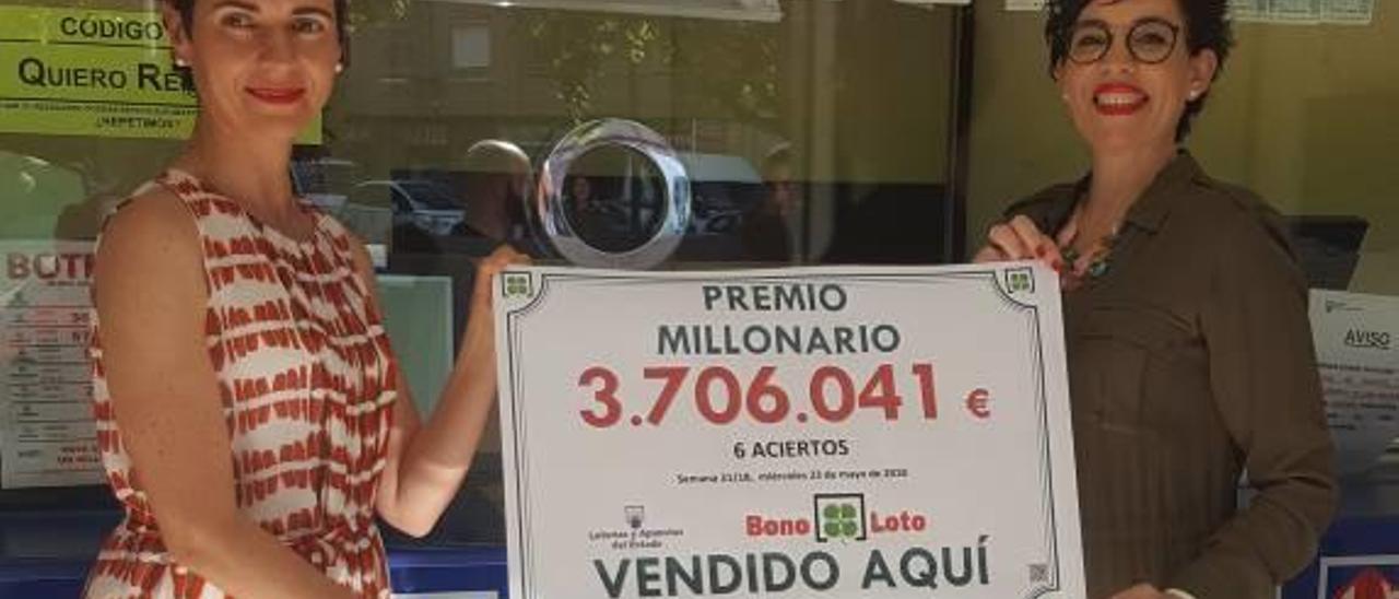 Las responsables de la oficina de lotería con el cartel del premio.