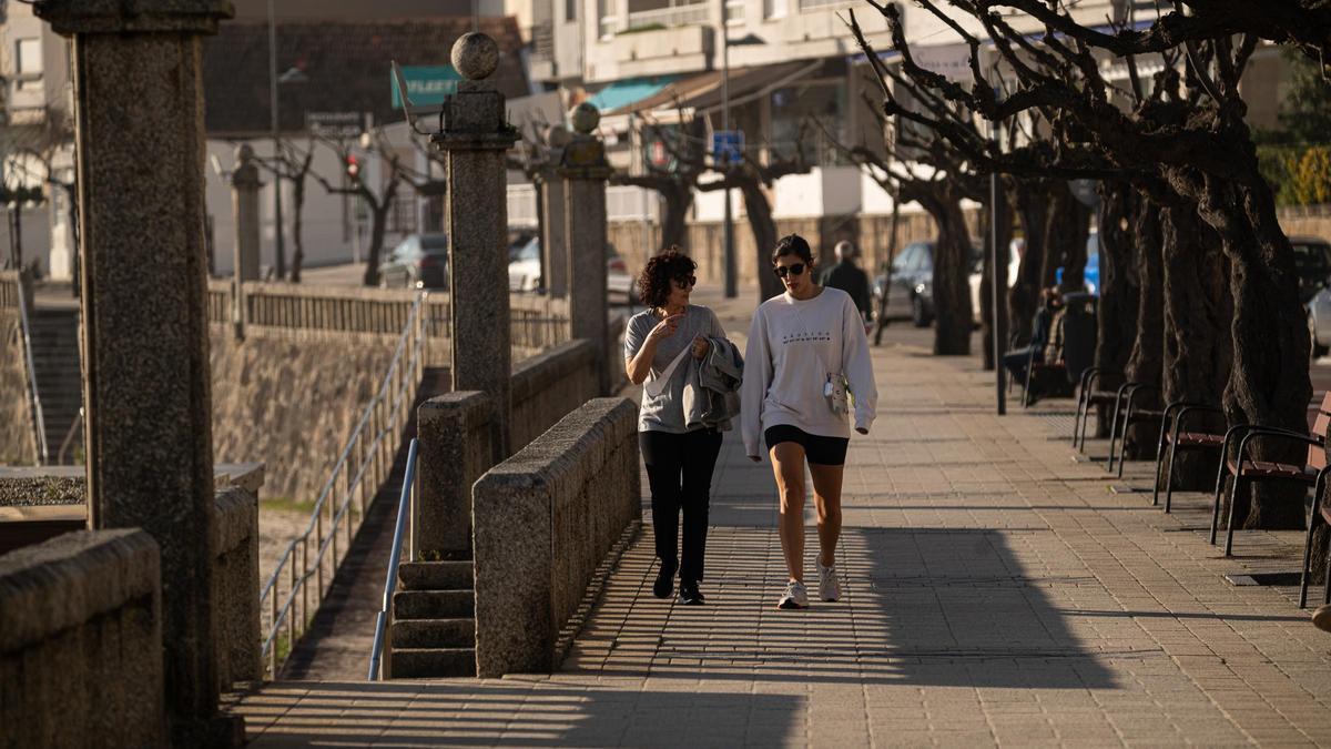 Dos personas pasean por la playa de Silgar (Sanxenxo) en una jornada de calor