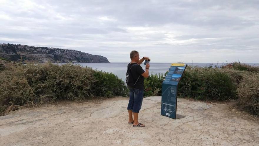 Un turista hace una fotografía al panel informativo del mirador des Delta.