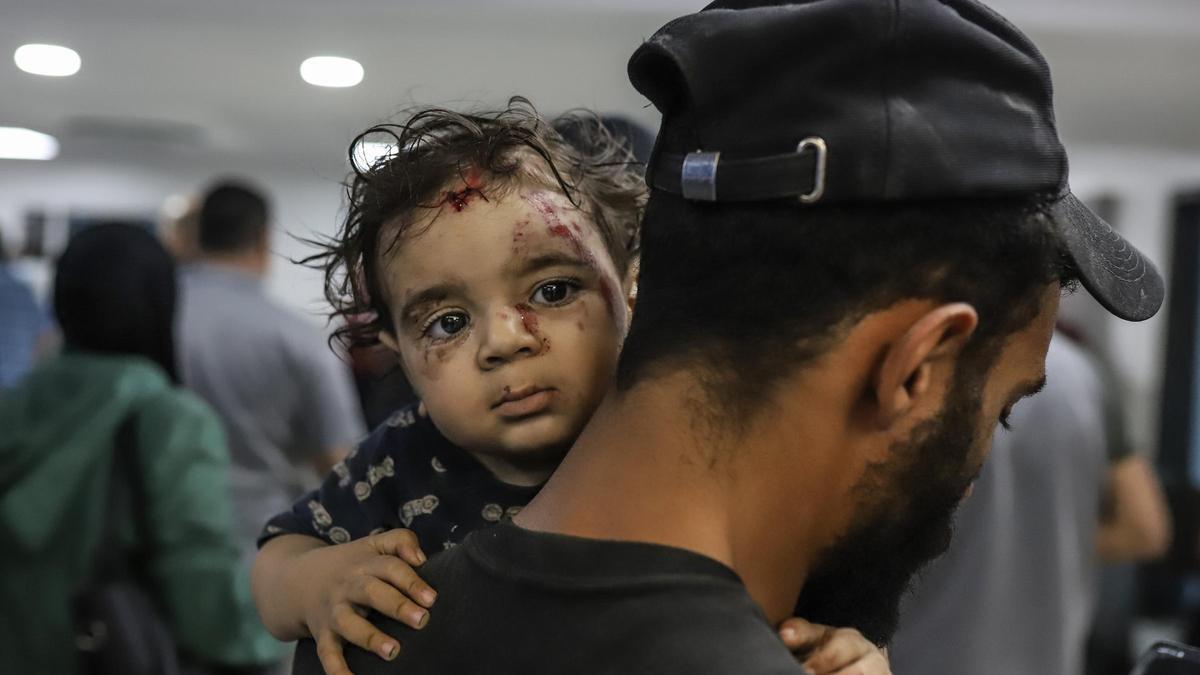 Un hombre lleva en brazos a una niña herida en Gaza.