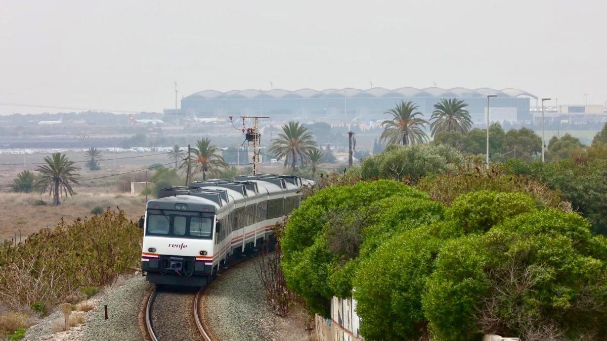 Un tren de cercanías por el trazado actual con el aeropuerto al fondo.