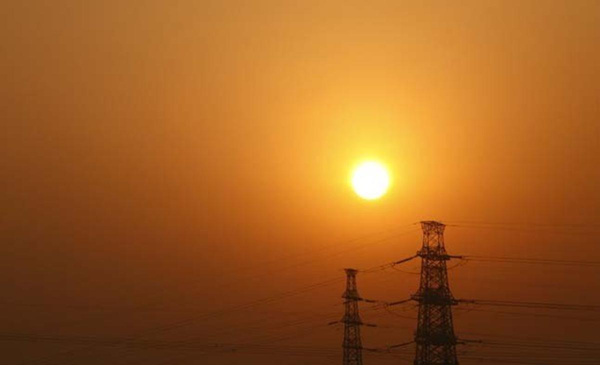 Imatge de la sortida de sol a Pequín (Xina), amb unes torres elèctriques de fons.