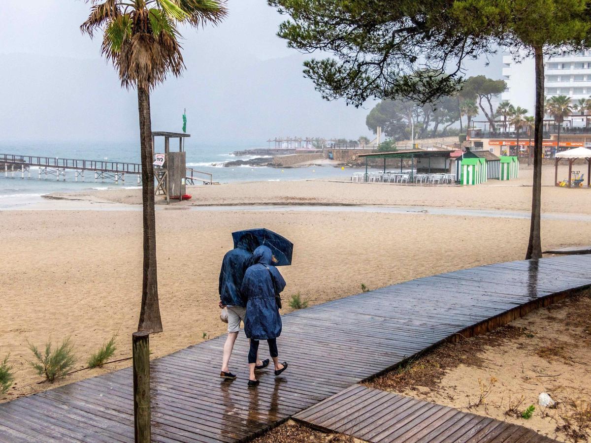 Spaziergänger an einem regnerischen Tag in Camp de Mar (Archivbild).