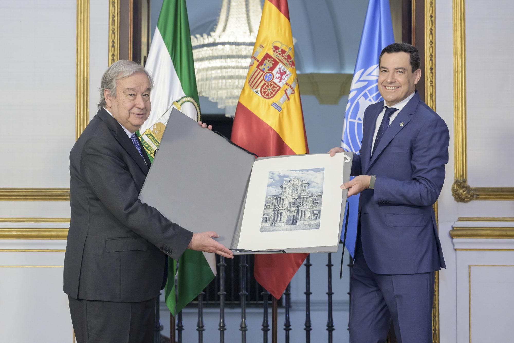 SEVILLA (ESPAÑA), 01/07/2025.- El presidente de la Junta de Andalucía, Juanma Moreno (d) entrega una imagen del Palacio de San Telmo al secretario general de las Naciones Unidas, António Guterres este martes en Sevilla, ciudad que acoge la IV Conferencia Internacional para el Desarrollo. EFE/ UN Photo/Manuel Elías/SOLO USO EDITORIAL/SOLO DISPONIBLE PARA ILUSTRAR LA NOTICIA QUE ACOMPAÑA (CRÉDITO OBLIGATORIO)