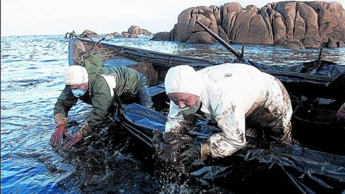 Dos pescadores de Santa Mariña (A Coruña), en plena la Costa da Morte, extraen chapapote del mar en diciembre del 2002.