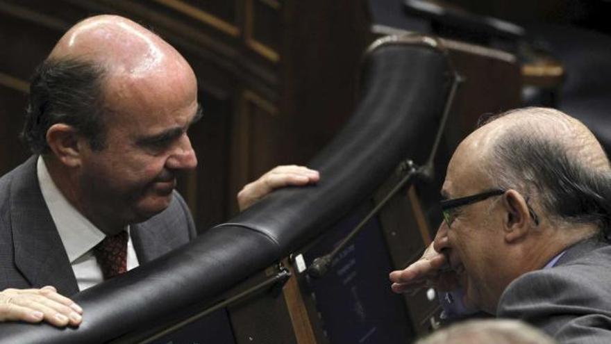 Cristóbal Montoro, a la derecha, se tapa la boca mientras conversa con Luis de Guindos, ayer, en el Congreso.