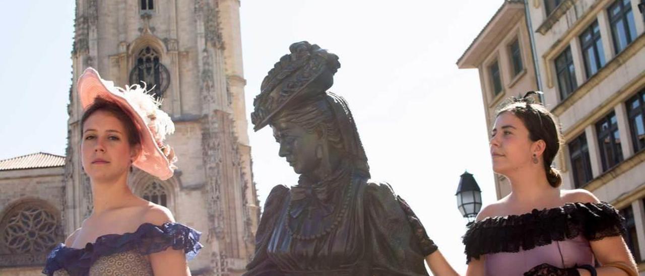 Ana Belén León con el nuevo vestido de Regenta y Andrea Holland, con el antiguo, posan en la plaza de la Catedral junto a la estatua que recuerda al personaje de Clarín.