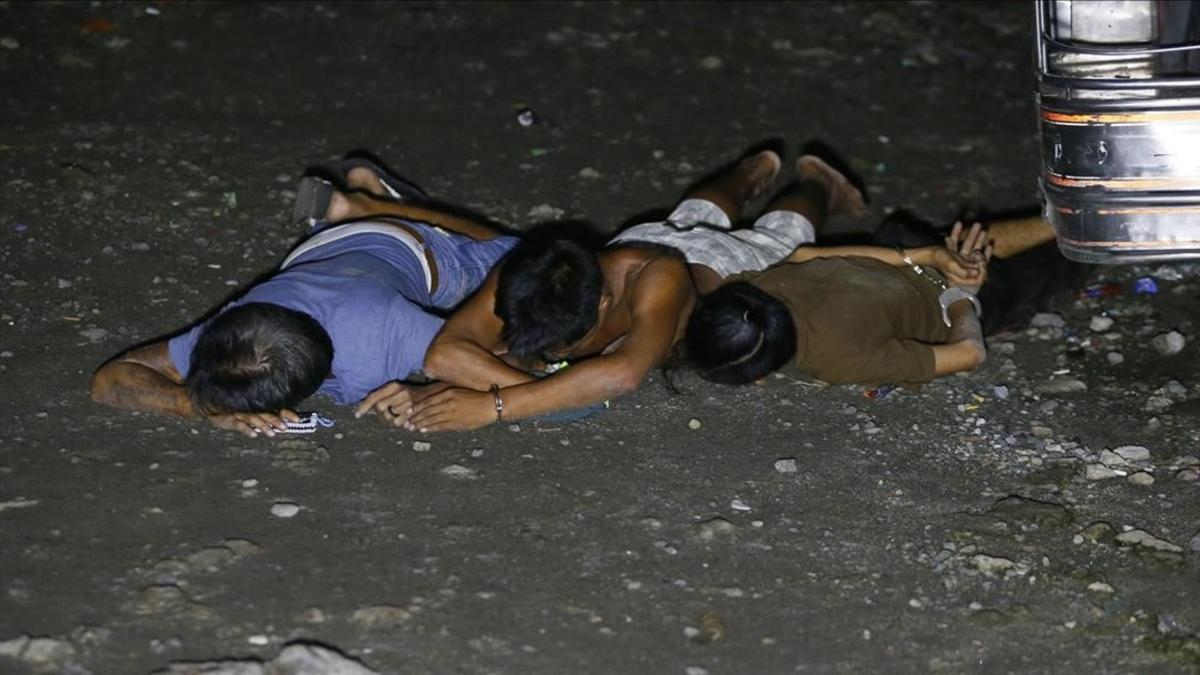Presuntos traficantes de droga, en el suelo, tras ser detenidos en una operación policial en Caloocan, al norte de Manila (Filipinas), este viernes.