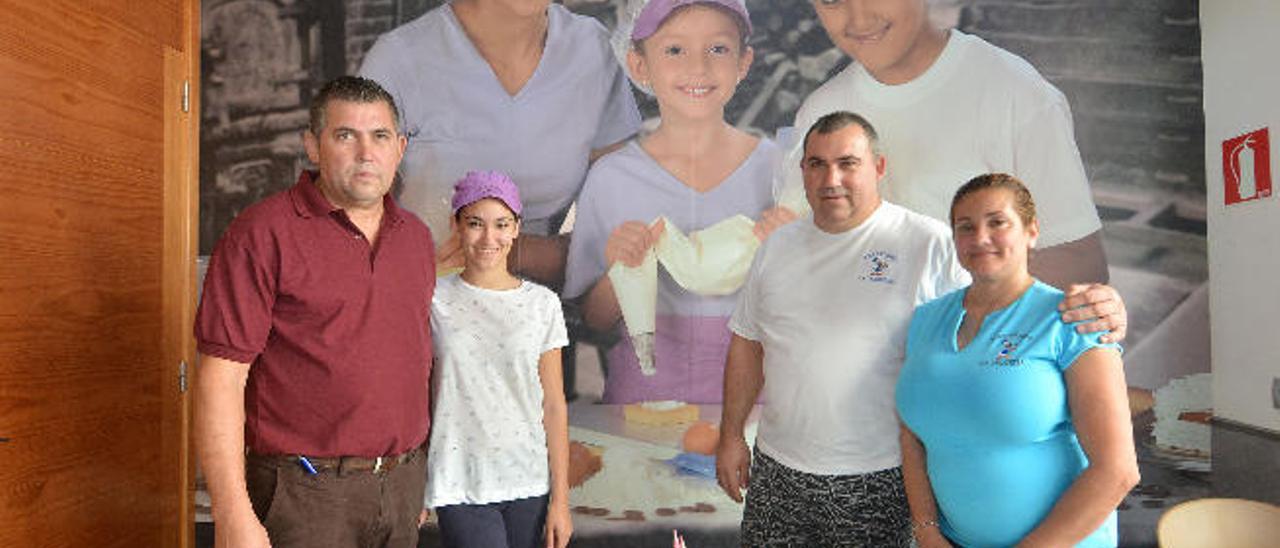 Jorge Medina, María Medina Cabrera, Pedro Medina y María Isabel, delante de la foto de sus hijos, María, Guacimara y Pedro en la pastelería de Vecindario