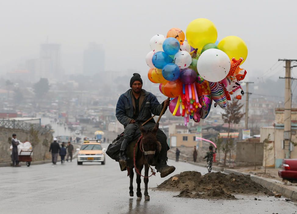 Un hombre afgano monta sobre su burro mientras lleva unos globos en la celebración de la llegada de la primavera en Kabul.