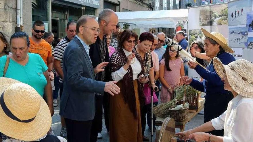 El alcalde, entre el numeroso público, contemplando el trabajo en los puestos de artesanos. // A. Hernández.