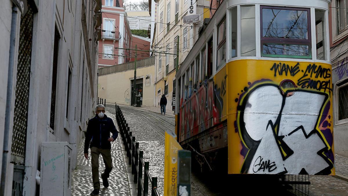 Un hombre con macarilla caminando por una calle de Lisboa durante la pandemia del coronavirus. // Pedro Fiuza