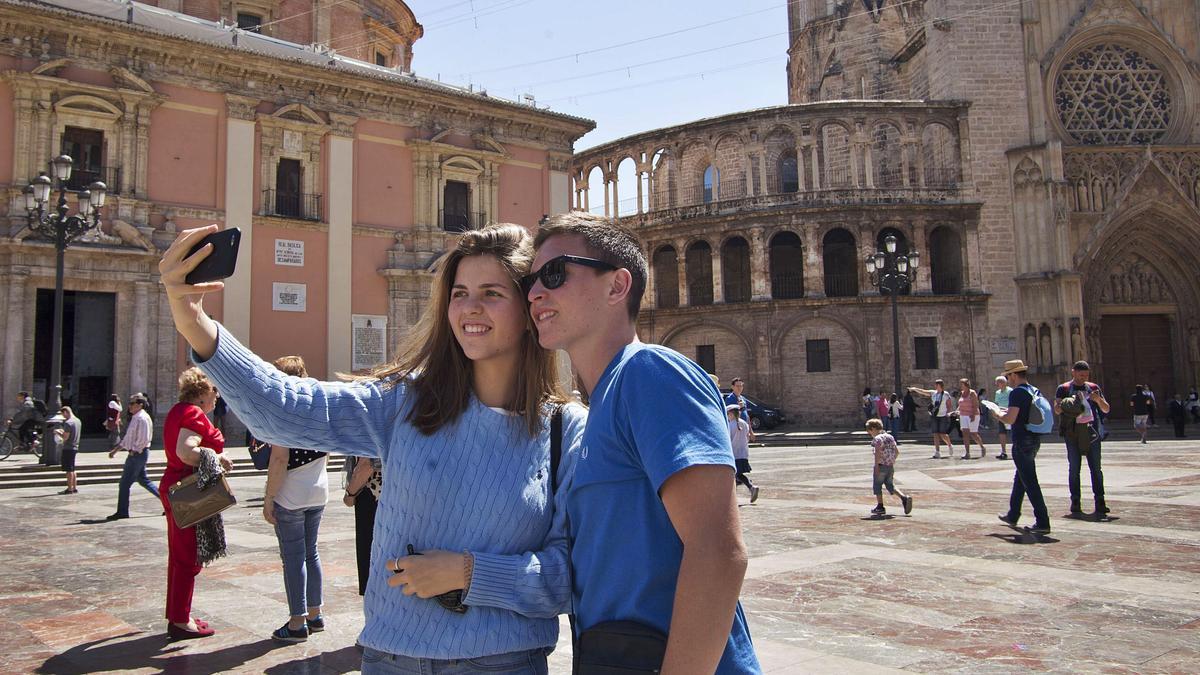 Una pareja de turistas se hace 
una foto en la plaza de la 
Virgen de València.  levante-emv