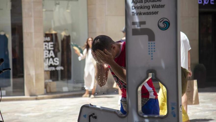 Un hombre refrescándose en una fuente de Palma.