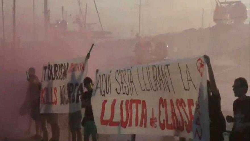 Jóvenes de Arran sostienen pancartas contra el turismo entre el humo de las bengalas. // Efe