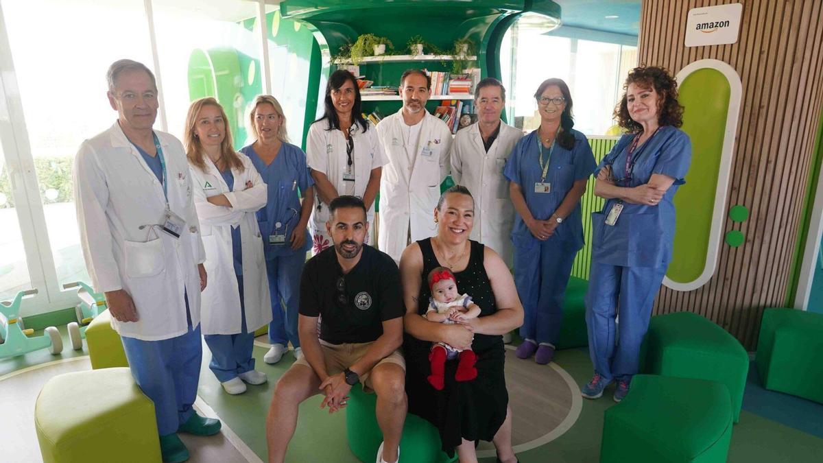 Los padres Rosa María Domínguez y David González, sujetan a su hija Aitana, junto al equipo de médicos de pediatría del Hospital Materno Infantil, donde ha sido operada por un problema de mandíbula.