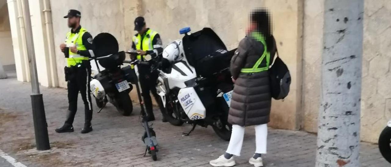 Agentes de la Policía Local multando a una usuaria de un patinete eléctrico.