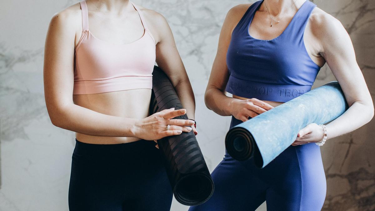 Dos personas sujetan sus esterillas de yoga