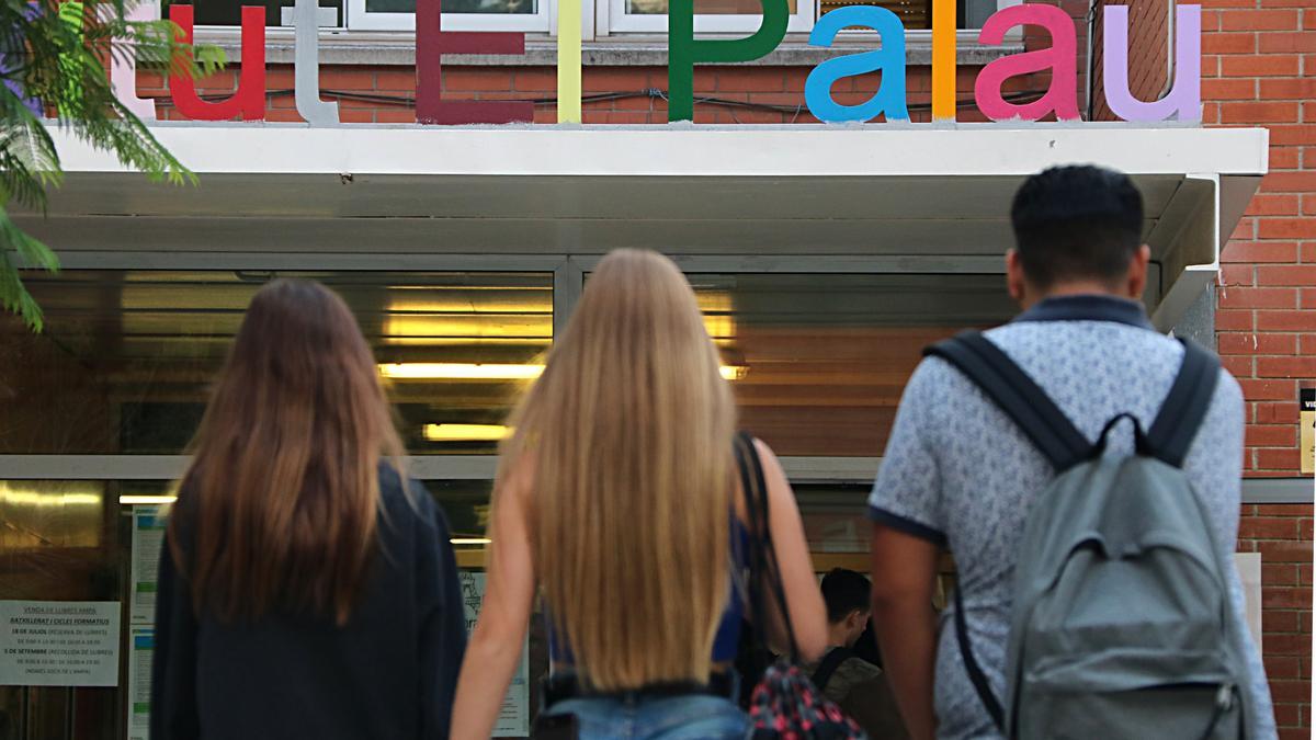 Pla tancat de l'entrada a l'IES El Palau de Sant Andreu de la Barca, amb tres alumnes accedint al centre el dia de l'inici de curs 2018-2019