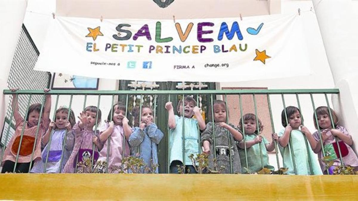 Alumnos de la escuela El Petit Príncep Blau, bajo un cartel reivindicativo, en el balcon de la guardería.