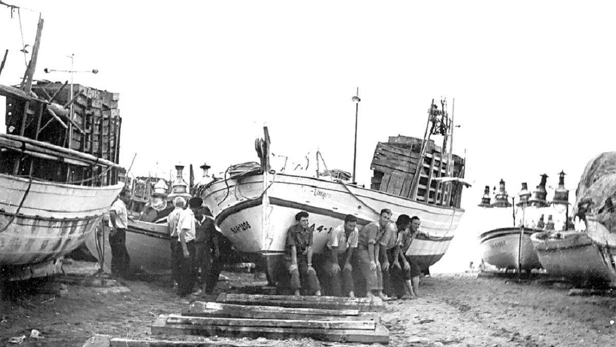 Un grup de pescadors empentant una barca a la platja de l'Escala als anys cinquanta.