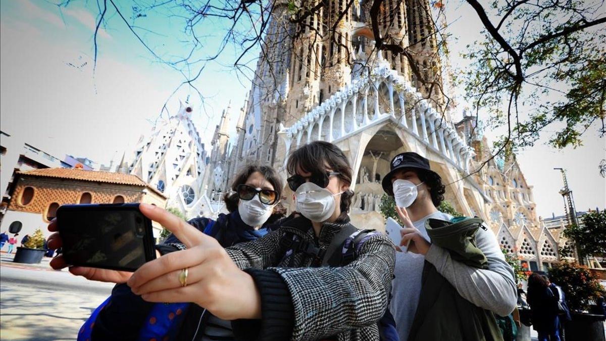 Turistas con mascarilla junto a la Sagrada Família