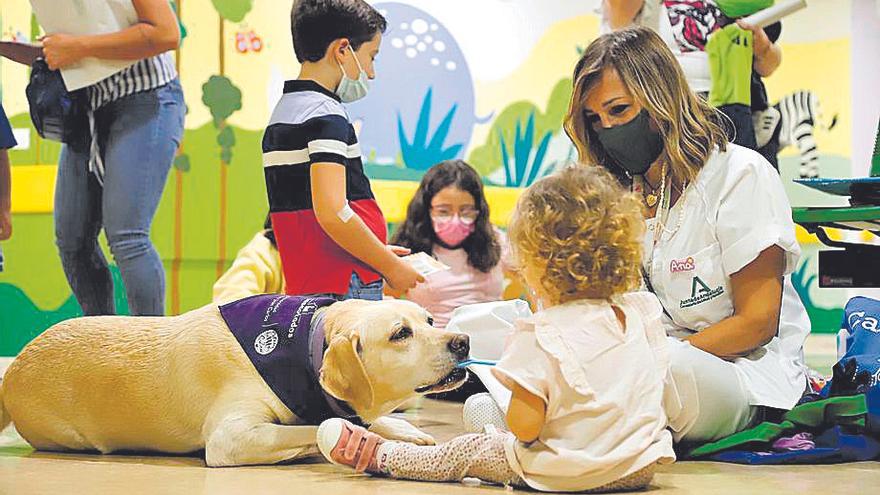 Ana Calvo, coordinadora de la Unidad de Actividades Motivacionales del hospital Reina Sofía, junto al perro Bourbon y pacientes.