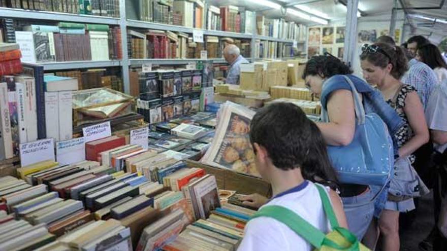 Visitantes de la feria observan, ayer, libros en una de las casetas. / víctor echave